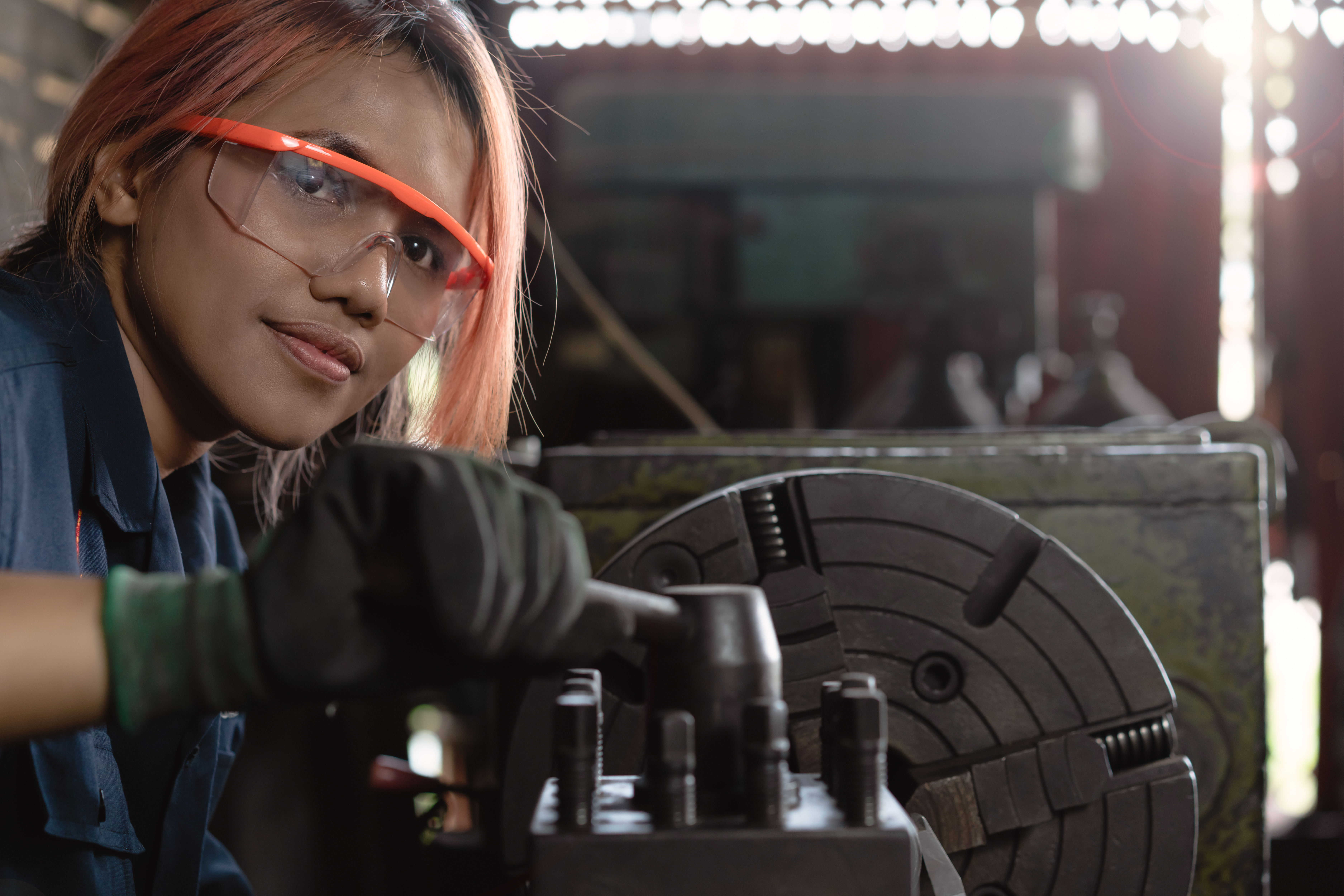 Young woman with safety glasses running machinery