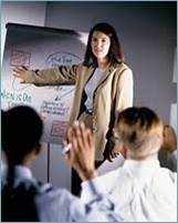 woman giving a presentation with two men watching.  One of the men has his hand raised.