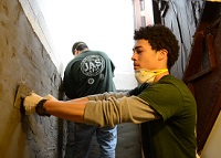 YouthBuild Student smoothing cement on wall