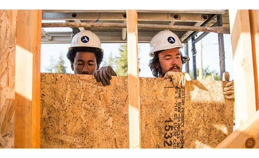 Two men working on building framing