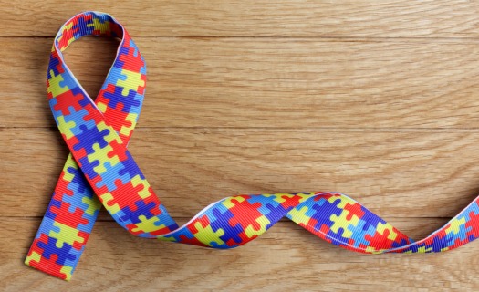 Colorful autism acceptance ribbon with red, yellow, and blue puzzle piece print.