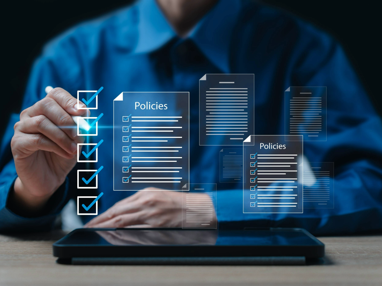 Man sitting at desk in front of tablet facing up with floating, transparent window that says "policies"