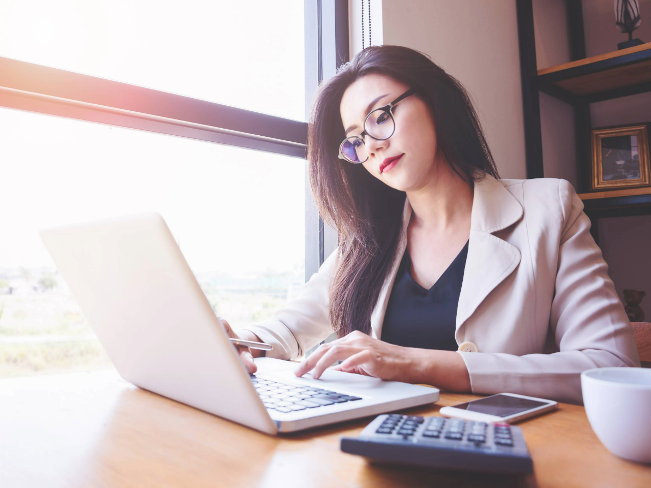Woman sitting at desk by a window working on laptop