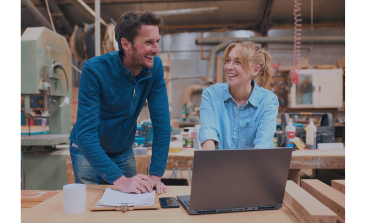 Man and woman in workshop in discussion while working on laptop